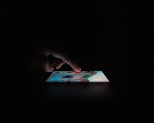 A close up of a person looking at a bright mobile phone screen in the dark