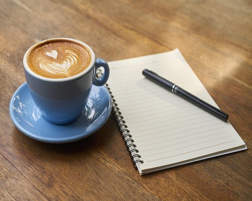 A cup of coffee next to a notebook in a bright cafe in Bogota