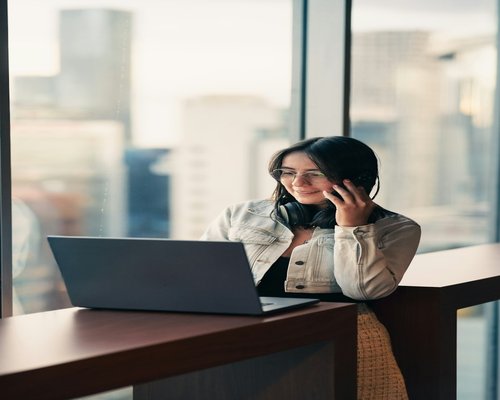 A person relaxing and looking away from a computer screen near a large window
